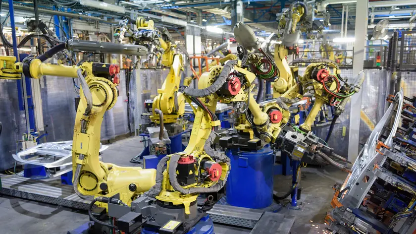 Robots welding body panels on production line in car factory