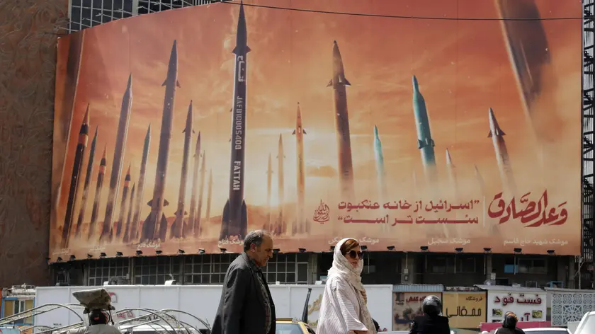 epa11293859 Iranians walk past an anti-Israel billboard carrying pictures of Iranian missiles and a sentence reading in Persian 'Israel is weaker than spider home' in Tehran, Iran, 22 April 2024. Tension between Iran and Israel continue since Iran's Islamic Revolutionary Guards Corps (IRGC) launched drones and missiles towards Israel on 13 April, following an airstrike on the Iranian embassy in Syria which Iran claimed was conducted by Israel. Iranian state media reported that three aerial objects were destroyed by air defense systems over the central city of Isfahan early morning on 19 April. EPA/ABEDIN TAHERKENAREH