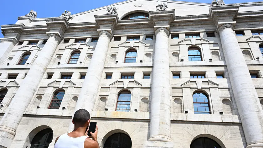 Una persona fotografa Palazzo Mezzanotte, l'edificio che ospita la Borsa Valori di Milano in piazza degli Affari, Milano, 6 agosto 2024. Le Borse europee si muovono attorno alla parità dopo una partenza leggermente positiva e il crollo di diversi mercati alla vigilia: gli indici azionari del Vecchio continente ondeggiano incerti, con Piazza Affari che sale dello 0,2% in un clima che rimane molto nervoso e volatile. ANSA7DANIEL DAL ZENNARO