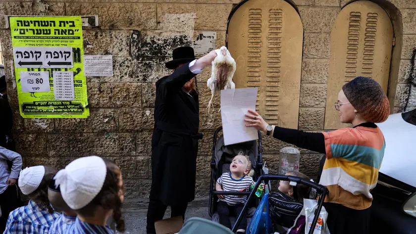 epa11652478 An ultra-Orthodox Jew swings a chicken purchased for the Kapparot ritual in the Mea Shearim neighborhood in Jerusalem, 10 October 2024. Kapparot begins by reciting a prayer and then spinning the bird over their head to release the sins accumulated over the past year, ahead of the high-holiday of Yom Kippur, the Day of Atonement. After the Kapparot ritual is performed the bird is slaughtered and donated to charity. EPA/ABIR SULTAN