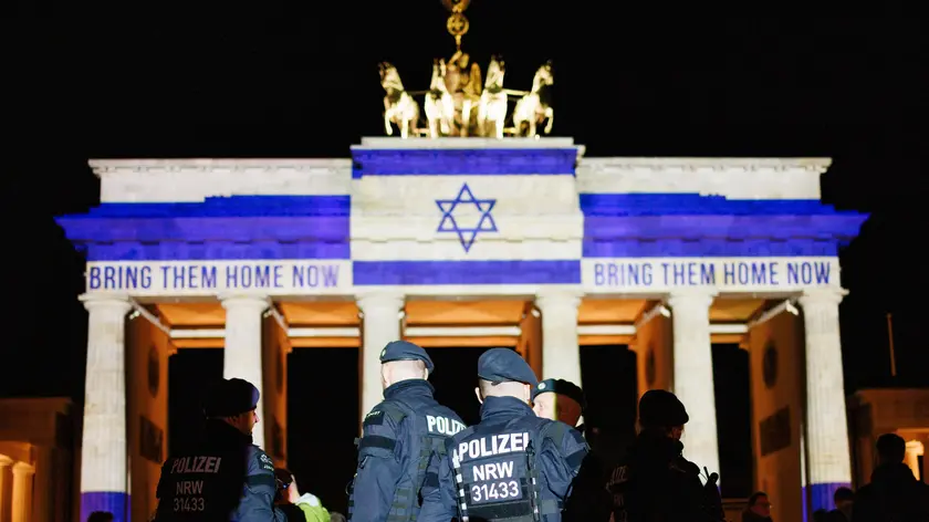 epaselect epa11648111 Police officers stand in a group in front of the Brandenburg Gate that is illuminated in the colors of the Israeli national flag in commemoration of the attack on Israel on 07 October and reads, in reference to the hostages, abducted by Hamas terror organization on 07 October 2023, 'Bring them home now' in Berlin, Germany, 07 October 2024. 07 October 2024 marks one year since the Palestinian militant group Hamas launched a surprise attack on Israel, killing 1,200, and one year since Israel began its war on Gaza, killing more than 41,000 and destroying the Palestinian enclave. EPA/CLEMENS BILAN