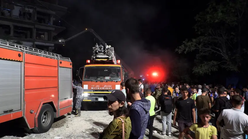 epa11649793 Syrian people stand near fire trucks at the site after missiles fell on a building in the Al-Mazzeh neighborhood in Damascus, Syria, 08 October 2024. At least seven people were killed and 11 others injured after three Israeli missiles targeted a residential building in Damascus, according to Syrian state news agency SANA, adding that rescuers are still working at the site of the strike. Israel did not immediately comment on the strike. EPA/STRINGER