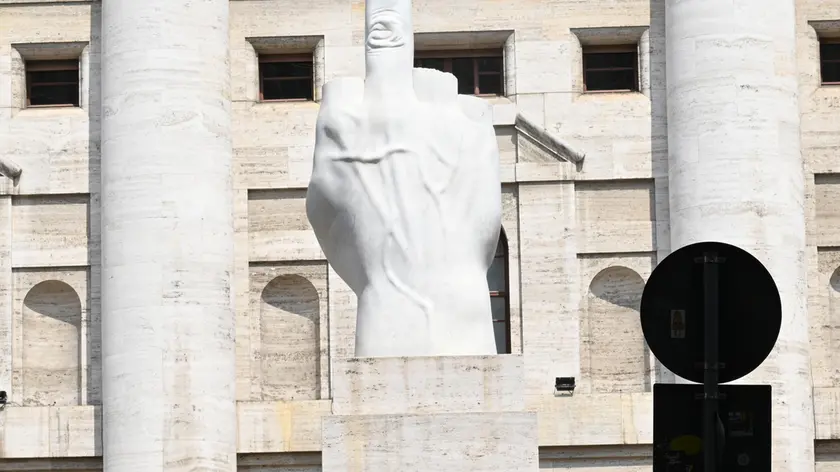 Una turista fotografa 'opera dell'artista italiano Maurizio Cattelan, “L. O. V. E.”, (acronimo di “libertà-odio-vendetta-eternità) espota davanti all'entrata di Palazzo Mezzanotte, l'edificio che ospita la Borsa Valori di Milano in piazza degli Affari, Milano, 6 agosto 2024. Le Borse europee si muovono attorno alla parità dopo una partenza leggermente positiva e il crollo di diversi mercati alla vigilia: gli indici azionari del Vecchio continente ondeggiano incerti, con Piazza Affari che sale dello 0,2% in un clima che rimane molto nervoso e volatile. ANSA7DANIEL DAL ZENNARO