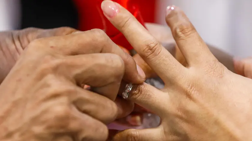 epa11151192 A couple shares wedding bands during a mass civil wedding ceremony marking Valentine's Day at a gymnasium in San Juan City, Metro Manila, Philippines 14 February 2024. A total of 57 couples were provided free matrimonial arrangements by the city government and served a reception banquet with relatives and loved ones. EPA/ROLEX DELA PENA
