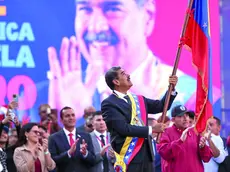 Il presidente Nicolas Maduro sventola la bandiera nazionale sul palco di una manifestazione a Caracas