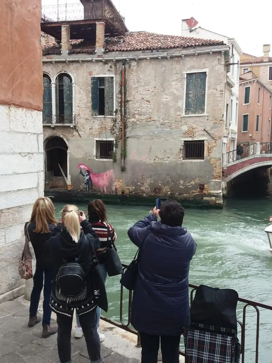 Venezia Biennale 2019: turisti appassionati fotografano a San Pantalon l'opera "migrant child" di Bansky