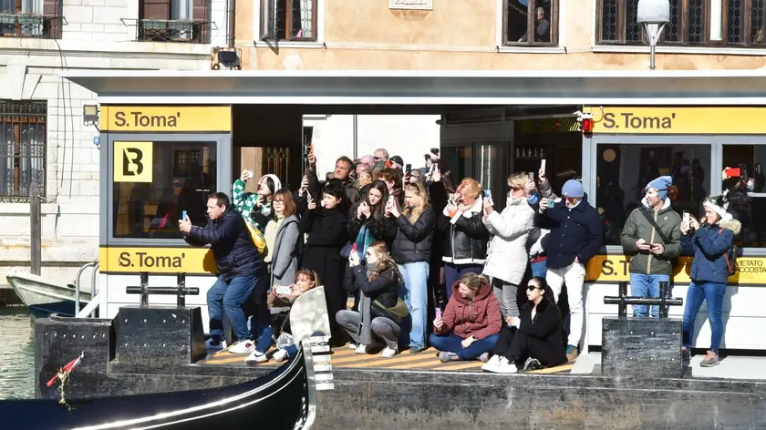 Turisti accalcati alla fermata di vaporetto per fotografare il corteo acqueo del Carnevale