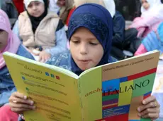 Una bambina legge un libro di testo italiano in una foto d'archivio