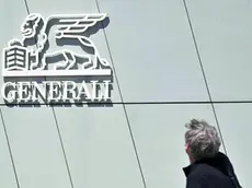 Una persona osserva il logo esposto sulla Torre Hadid o Torre Generali, sede degli uffici di Milano del Gruppo