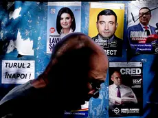 Un passante a Bucarest davanti a un cartellone pubblicitario (Ansa/Epa)