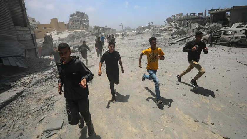 Civili corrono al riparo dopo un attacco aereo israeliano a ovest di Gaza City