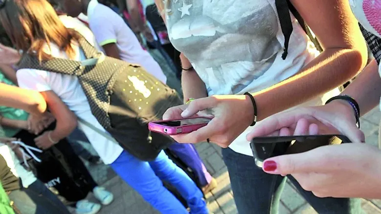 Giovani con il cellulare, si è acceso il dibattito sull’ipotesi di vietarlo