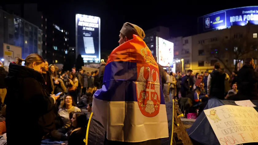 Un ragazzo avvolto nella bandiera serba durante le manifestazioni dei mesi scorsi a Belgrado