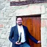 Massimiliano Zufferli con una bottiglia del suo spumante davanti a un'antica cantina delle Valli del Natisone