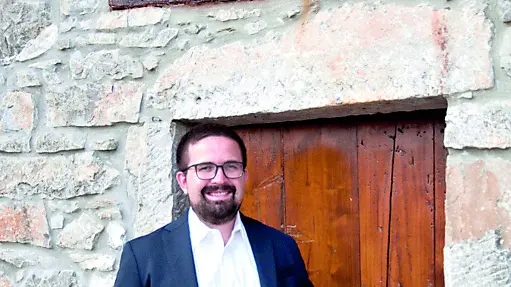 Massimiliano Zufferli con una bottiglia del suo spumante davanti a un'antica cantina delle Valli del Natisone