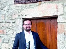 Massimiliano Zufferli con una bottiglia del suo spumante davanti a un'antica cantina delle Valli del Natisone
