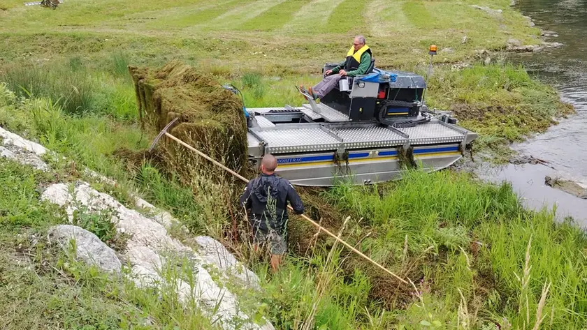 La falciatrice anfibia al lavoro nel lago di Alleghe: taglia le alghe e le porta a riva
