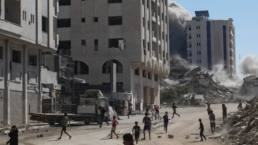 Palestinesi in strada dopo un attacco aereo di Israele a un edificio residenziale di Gaza City