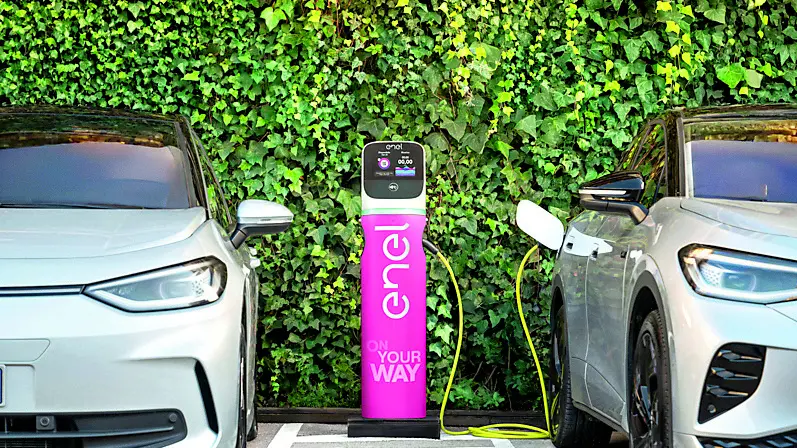Due auto elettriche ferme parcheggiate ad una colonnina per ricaricare la batteria