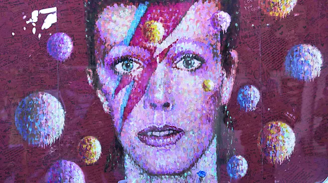 Fiori e candele davanti al murale dedicato a David Bowie in una strada di Londra