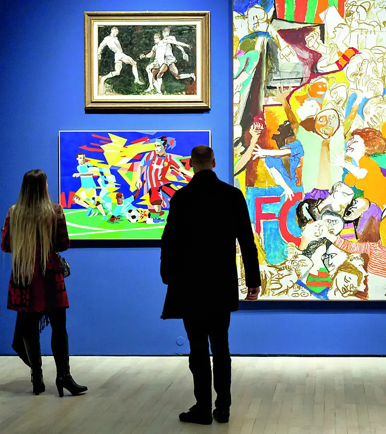 Visitatori davanti ad alcune delle tele in mostra al Mart dedicate al calcio