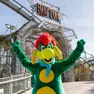 Prezzemolo, la mascotte di Gardaland, davanti a Raptor, una delle attrazioni simbolo del parco