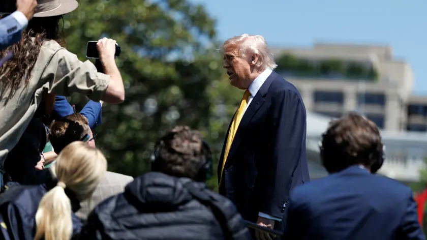 Donald Trump parla con i giornalisti prima della partenza per la Cina (foto Epa)