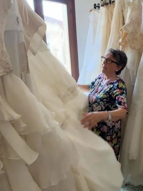 Rosella Lorenzetto, referente della Caritas di Paese, tra gli abiti da sposa dell'Atelier solidale