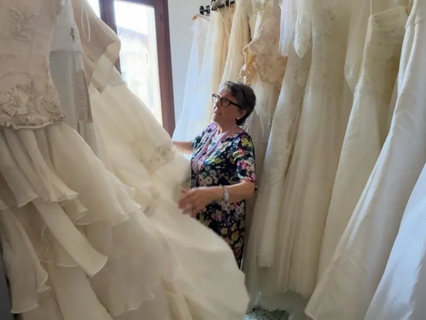 Rosella Lorenzetto, referente della Caritas di Paese, tra gli abiti da sposa dell'Atelier solidale