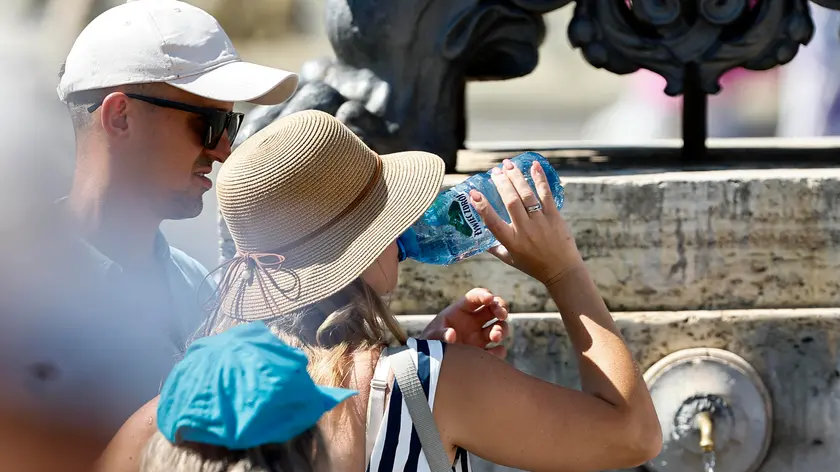 Turisti cercano refrigerio dal caldo a una fontanella (foto Ansa)