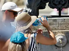 Turisti cercano refrigerio dal caldo a una fontanella (foto Ansa)