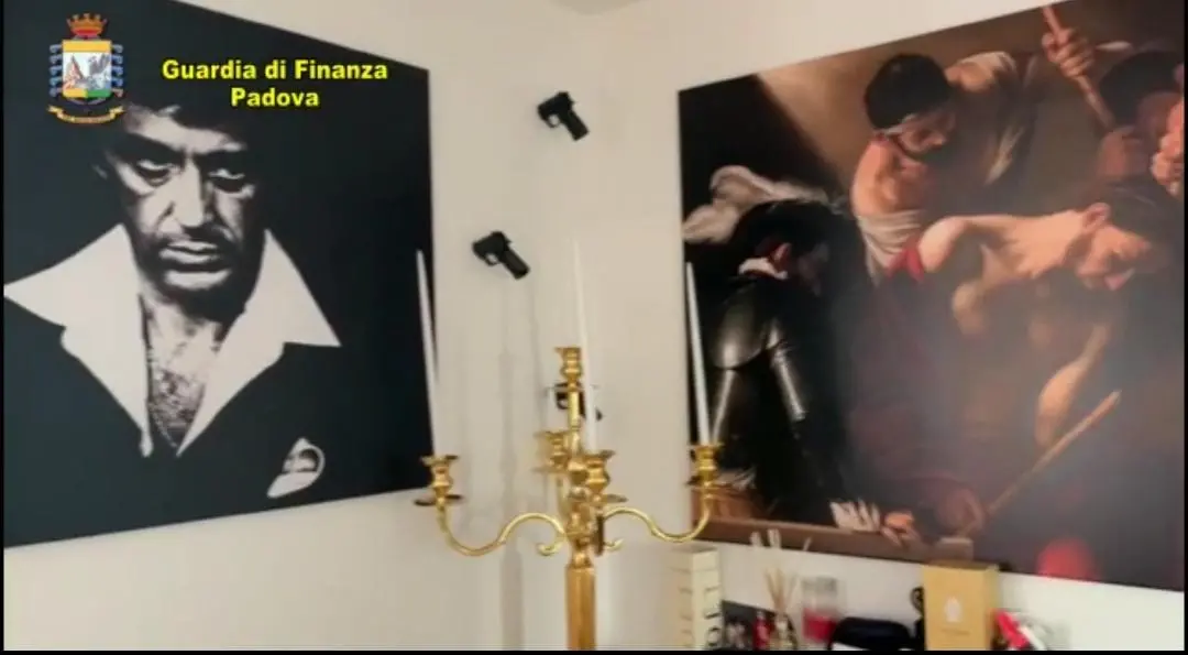 Operazione zona rossa - maxi truffa alle aziende venete smantellata dalla Finanza- la gigantografia del malavitoso Tony Montana e le pistole appese al muro nell'appartamento milanese di William Alfonso Cerbo nella CityLife