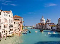 The Grand Canal and Santa Maria della Salute church in Venice, Italy. Boats moving on the river under a clear blue summer sky.