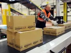 epa02503792 An employee of the online-retailer Amazon puts packages onto a conveyor band at the logistics centre in Bad Hersfeld, Germany, 20 December 2010. The recent weather causes many problems concerning the delivery of Christmas packages. EPA/UWE ZUCCHI