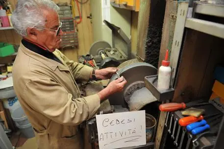 Un artigiano in provincia di Pisa con il cartello di cedesi attivita' all' interno del suo laboratorio. ANSA/STRINGER