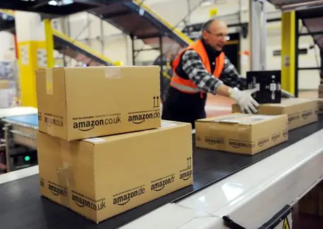 epa02503792 An employee of the online-retailer Amazon puts packages onto a conveyor band at the logistics centre in Bad Hersfeld, Germany, 20 December 2010. The recent weather causes many problems concerning the delivery of Christmas packages. EPA/UWE ZUCCHI