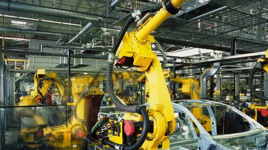 yellow robots welding cars in a production line