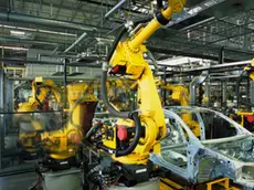 yellow robots welding cars in a production line