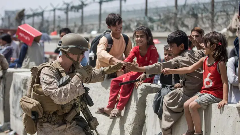 In this image provided by the U.S. Marine Corps, a Marine with Special Purpose Marine Air-Ground Task Force-Crisis Response-Central Command (SPMAGTF-CR-CC) plays with children waiting to process during an evacuation at Hamid Karzai International Airport in Kabul, Afghanistan, Friday, Aug. 20, 2021. (Sgt. Samuel Ruiz/U.S. Marine Corps via AP)