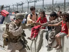 In this image provided by the U.S. Marine Corps, a Marine with Special Purpose Marine Air-Ground Task Force-Crisis Response-Central Command (SPMAGTF-CR-CC) plays with children waiting to process during an evacuation at Hamid Karzai International Airport in Kabul, Afghanistan, Friday, Aug. 20, 2021. (Sgt. Samuel Ruiz/U.S. Marine Corps via AP)