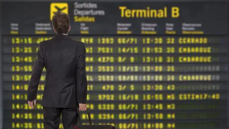 Businessman with a briefcase on a background of departure board at airport
