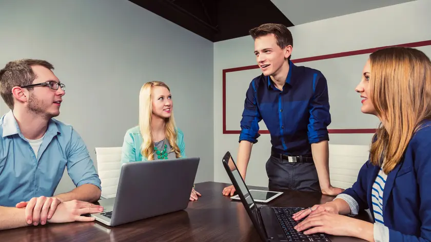 Young millennial businessman speaking to a group of young professionals in a conference room in a place of business; Sherwood Park, Alberta, Canada