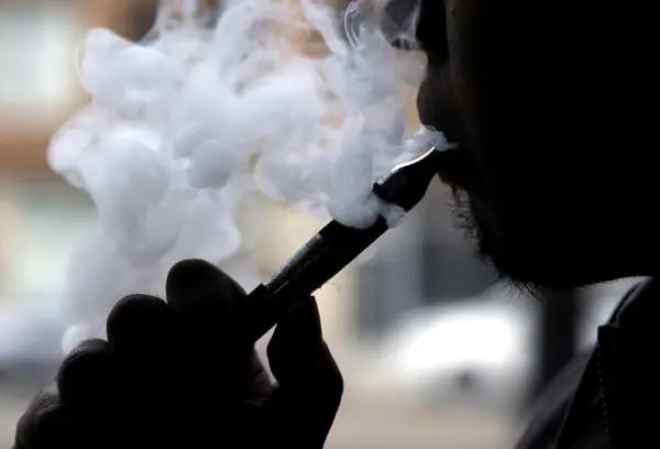 FILE - In this April 23, 2014 file photo, a man smokes an electronic cigarette in Chicago. On Tuesday, Jan. 5, 2016, the U.S.'s lead public health agency focused its attack on electronic cigarettes on the issue of advertising, saying too many kids see the ads. There are bans on TV commercials and some other types of marketing for regular cigarettes but there are no restrictions on advertisements for e-cigarettes. Most states, though, ban the sale of e-cigarettes to minors. (ANSA/AP Photo/Nam Y. Huh, File) [CopyrightNotice: Copyright 2016 The Associated Press. All rights reserved. This material may not be published, broadcast, rewritten or redistribu]
