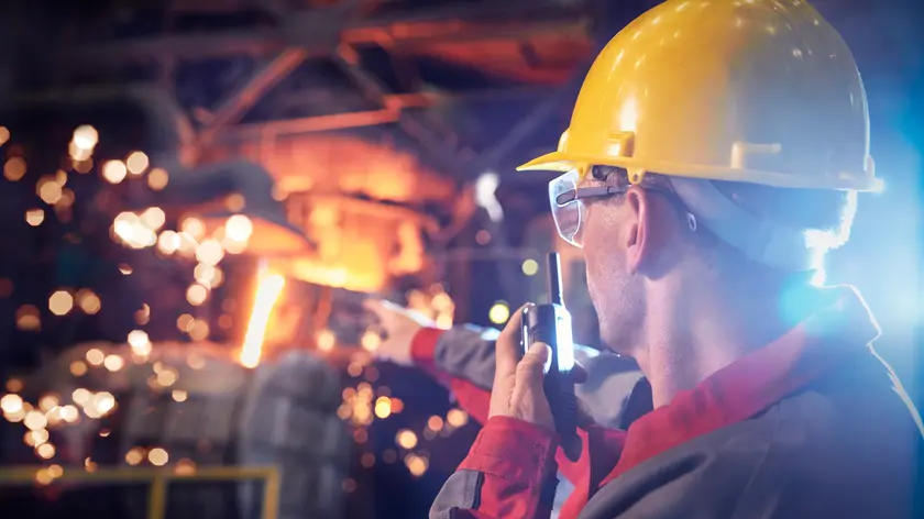 Steelworker talking, using walkie-talkie in steel mill