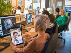 Creative businesswoman video chatting with businessman on digital tablet in open plan office