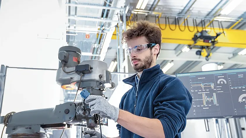 Robotics engineer fitting sensors to traditional engineering lathe in robotics research facility