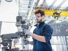 Robotics engineer fitting sensors to traditional engineering lathe in robotics research facility