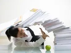 A woman in an office with a large pile of paper.