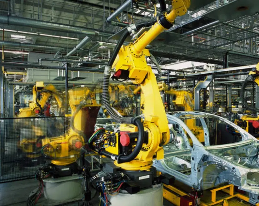 yellow robots welding cars in a production line