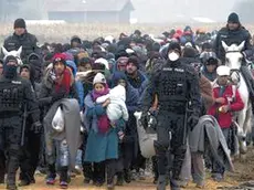 Escorted by police, migrants move through fields after crossing from Croatia, in Rigonce, Slovenia, Tuesday, Oct. 27, 2015. The European Union is lashing member countries for dragging their feet on providing funds and experts to help manage Europe's biggest refugee emergency in decades. (ANSA/AP Photo/Darko Bandic)
